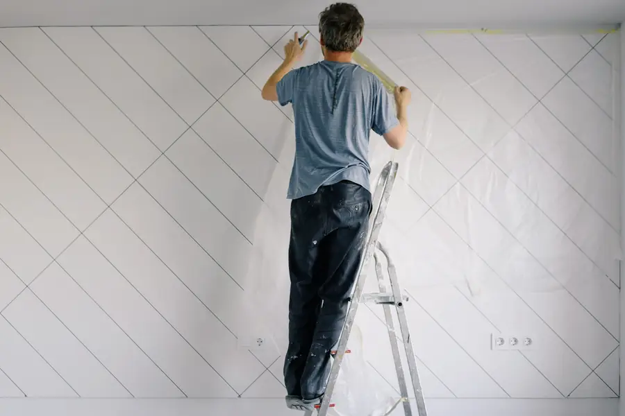 Peintre sur un escabeau préparant un mur avant la peinture